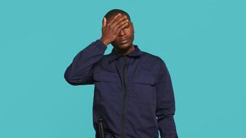Portrait of tired security guard suffering from painful headache while overseeing premises. Private law enforcement worker feeling ache from fatigue, studio backdrop, camera A video