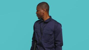Portrait of security guard looking around while overseeing premises. Private law enforcement worker doing surveillance job, inspecting location, studio backdrop, camera A video