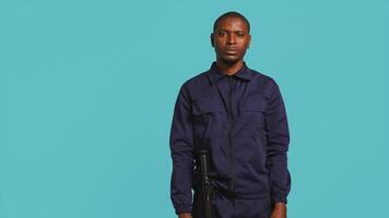 porträtt av leende säkerhet ombud säkring tilldelad posta, isolerat mot studio bakgrund. afrikansk amerikan väktare beredd till hantera säkerhet överträdelser och diffus spänd situationer, kamera b video