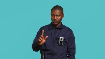Sécurité garde empêcher criminel activité, menaçant suspects avec actif caméra corporelle. portrait de menaçant garde du corps montrer du doigt vers Sécurité corps caméra, studio arrière-plan, caméra une video