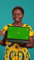 Vertical Confident happy person posing with a copy space mockup on laptop, create an advertisement with isolated display in studio. Young woman in ethnic attire with floral elements. Camera B. video