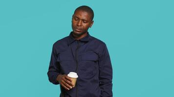 porträtt av säkerhet ombud användningar kaffe kopp till förbli energiserad medan säkring tilldelad posta, studio bakgrund. väktare förbrukande koffeinhaltig dryck till vara kapabel till hantera säkerhet överträdelser, kamera en video