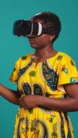 Vertical Happy confident woman uses vr headset with 3d visual simulation, wearing virtual reality smart glasses for a modern high tech experience. Person in traditional tribal clothes. Camera B. video