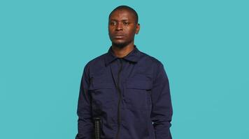 Security guard tasked with preventing criminal activity and detaining suspects stealing, damaging property, or performing other crimes. Portrait of intimidating bodyguard, studio background, camera A video