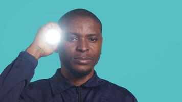 Headshot portrait of security guardian catching intruders with flashlight. Close up shot of private law enforcement employee detecting trespassers with lantern, studio backdrop, camera A video