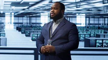 System administrator looking at holograms in data center, monitoring equipment. Employee in server farm interacting with futuristic augmented reality AI visualization, camera A video