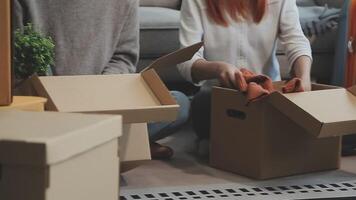 Young couple relaxing sitting on the sofa using the computer laptop around cardboard boxes, very happy moving to a new house. video