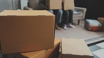 Young couple relaxing sitting on the sofa using the computer laptop around cardboard boxes, very happy moving to a new house. video