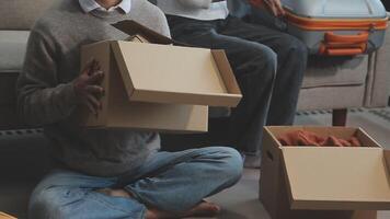 Young couple relaxing sitting on the sofa using the computer laptop around cardboard boxes, very happy moving to a new house. video
