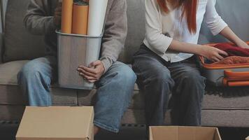 Young couple relaxing sitting on the sofa using the computer laptop around cardboard boxes, very happy moving to a new house. video