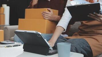 Young couple relaxing sitting on the sofa using the computer laptop around cardboard boxes, very happy moving to a new house. video