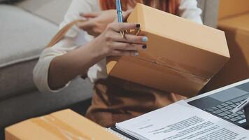 Young couple relaxing sitting on the sofa using the computer laptop around cardboard boxes, very happy moving to a new house. video