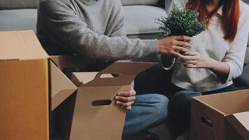 Young couple relaxing sitting on the sofa using the computer laptop around cardboard boxes, very happy moving to a new house. video