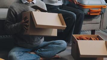 Young couple relaxing sitting on the sofa using the computer laptop around cardboard boxes, very happy moving to a new house. video