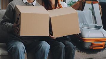 Young couple relaxing sitting on the sofa using the computer laptop around cardboard boxes, very happy moving to a new house. video