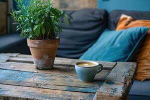 A coffee cup sits on a wooden table next to a potted plant photo