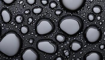 Close-up of water droplets on a black surface, creating a pattern of circles photo