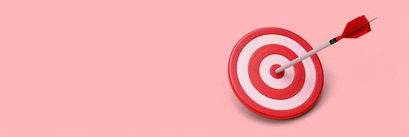 A red arrow has hit the center of a white and red bullseye target against a pink background photo