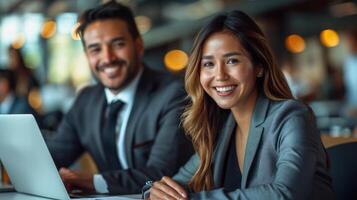 Two business professionals smiling and working on a laptop in a modern office setting photo