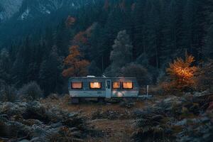 A caravan parked in a tranquil forest setting with misty mountains in the background during twilight photo