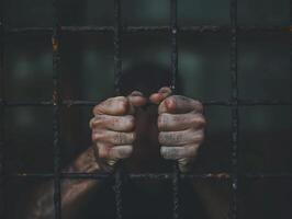 A close-up of a persons hands gripping the bars of a cell, showcasing the despair and longing for freedom photo