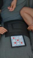 A group is playing TicTacToe on a tablet at home, having a casual and interactive time video