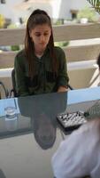 Two young women engaged in a game of chess outside, seated at a glass table in a park setting video