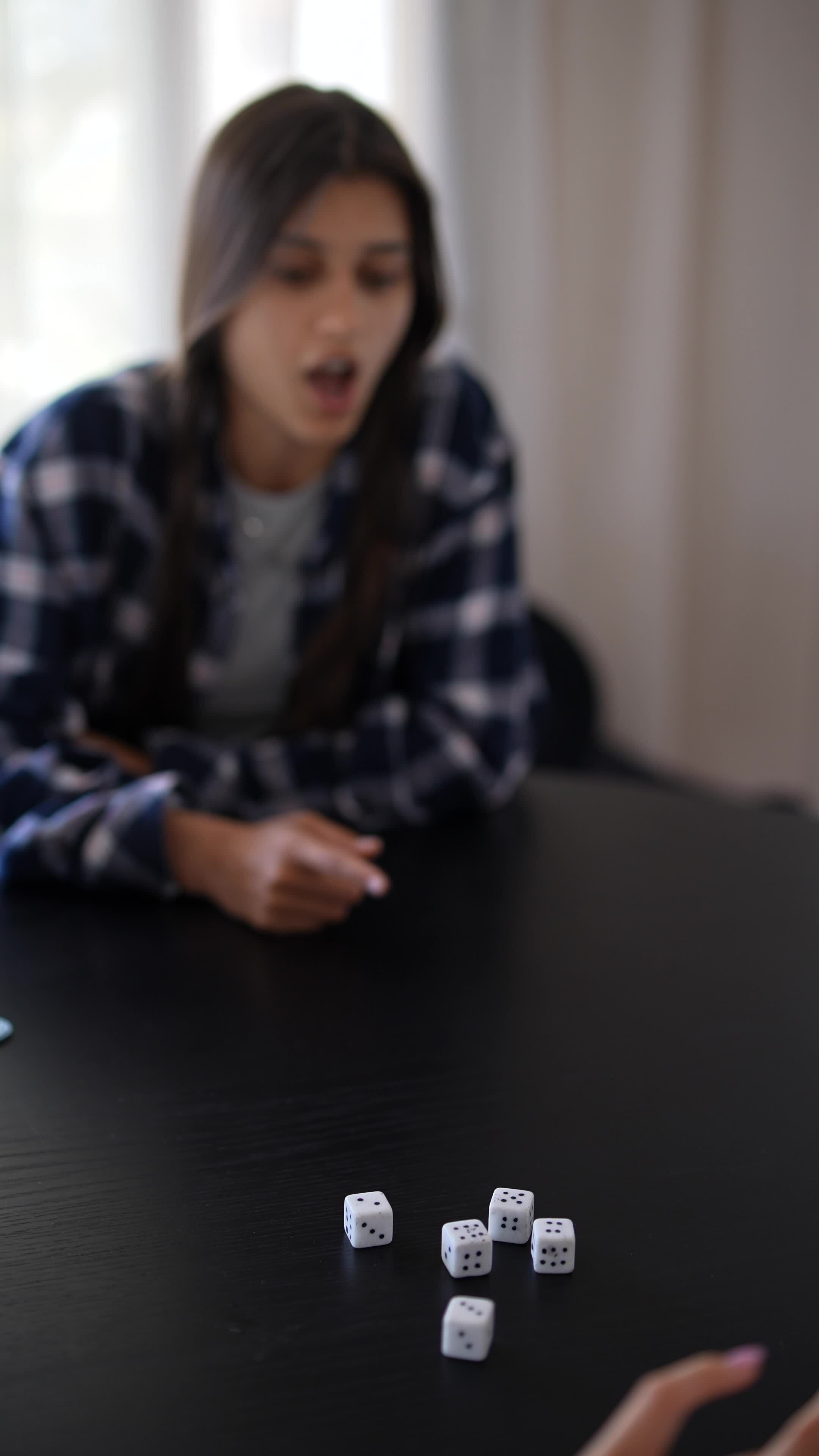 A woman is playing a game with dice on a table, displaying