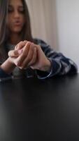 A young woman at a table, focusing on fidgeting with an object by using her hands video