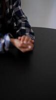 A person in a plaid shirt is playing dice on a black table, displaying concentration video