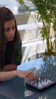 In a calm setting, a youthful female is serenely engaging in a game of chess under the open sky video