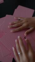 Hands arranging red playing cards on a tabletop, playing a game of strategy and skill video
