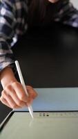 A person is engaged in rolling dice and using a digital pen on a tablet while sitting at a desk video
