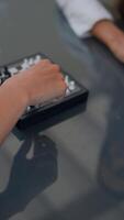 The hands are strategically moving chess pieces on a reflective surface during a game video