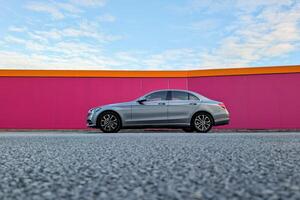 Grey modern automobile parked in front of pink wall, vehicle and transport, automotive background photo