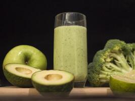 Fresh green smoothie in glass with avocado lime, broccoli, apple, cucumber around. Ideal smoothie for wellness, healthy eating, and detox. nutritious ingredients and refreshing taste of this smoothie. photo