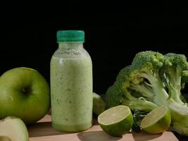 Fresh green smoothie in bottle surrounded by avocado, lime, broccoli, apple cucumber.Ideal for smoothie enthusiasts healthy eating and wellness videos Boost your content with this nutritious smoothie. photo