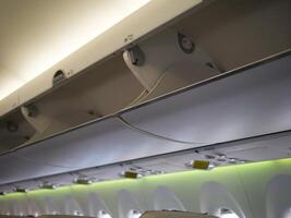 Upper part of aircraft cabin where bags are stored. Perfect for travel and aviation content. Aircraft overhead storage area shown in detail. Capture convenience and functionality of aircraft design. photo