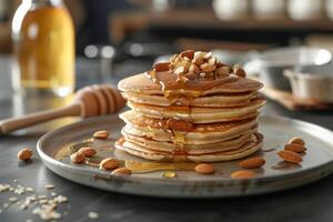 Stack of pancakes topped with honey and almonds on a plate photo