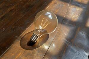 Vintage light bulb on a wooden floor with sunlight and shadows creating a warm atmosphere photo