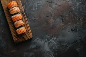 Sushi rolls with salmon on a wooden board against a dark textured background photo