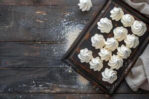 Delicate meringue cookies on a rustic wooden board, sprinkled with flour, top view photo