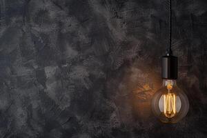 Vintage light bulb glowing against dark textured background photo