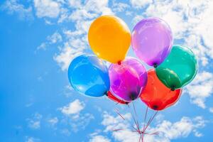 Bright colorful balloons against a blue sky with clouds photo