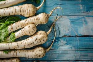 Fresh horseradish roots on a rustic blue painted wooden background photo