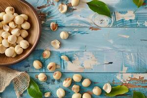 Macadamia nuts in a bowl and scattered on a rustic blue wooden surface photo