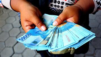 hand holding a pile of fifty thousand rupiah banknotes photo