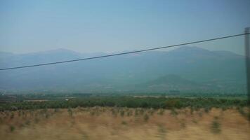 Expansive Countryside with Rolling Green Fields and Distant Mountain Range under Clear Blue Sky on a Sunny Day video