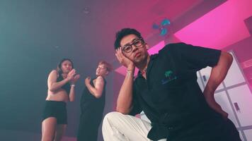 Man posing confidently with dancing women in background video