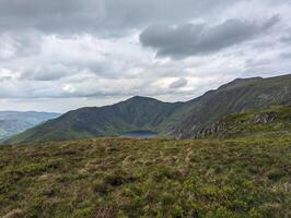Scenic Mountain Landscape Under Moody Sky with Green Hills and Valleys photo